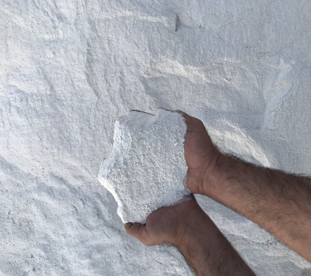 Hand holding a white mineral sample